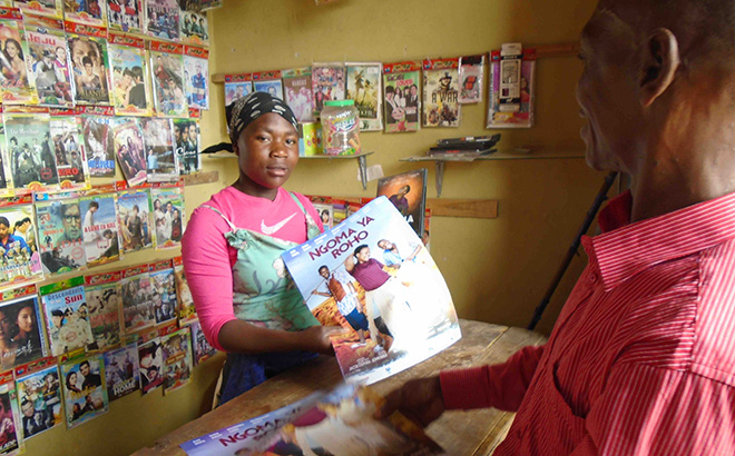 movie vendor holding Ngoma Ya Roho poster and DVD