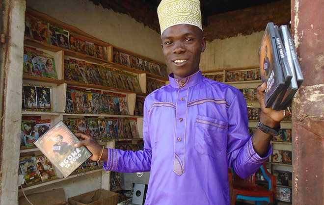movie vendor holding Ngoma Ya Roho DVDs